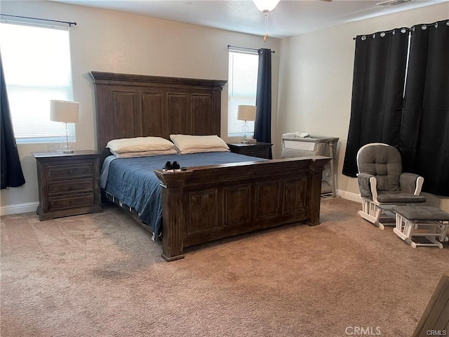 bedroom featuring visible vents, multiple windows, baseboards, and light colored carpet