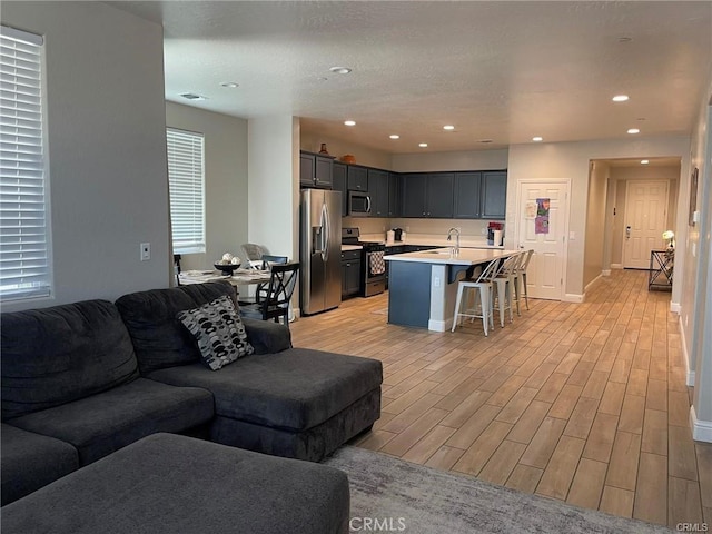 living area featuring light wood-style flooring, visible vents, baseboards, and recessed lighting