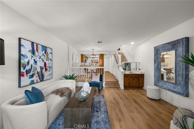 living area with stairway, wood finished floors, visible vents, and baseboards