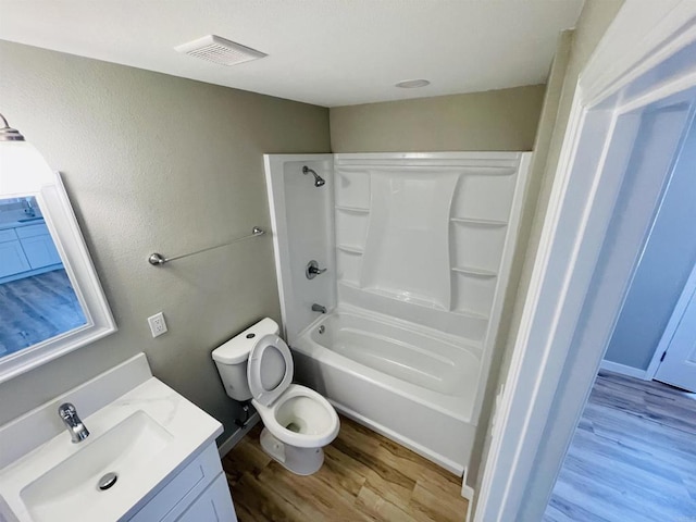 bathroom featuring toilet, wood finished floors, vanity, visible vents, and shower / bathing tub combination