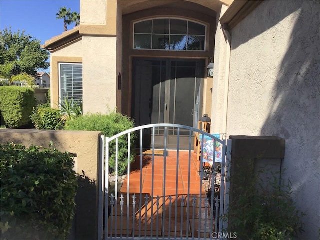 doorway to property with a gate and stucco siding