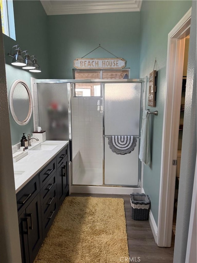 bathroom with ornamental molding, a shower stall, and wood finished floors