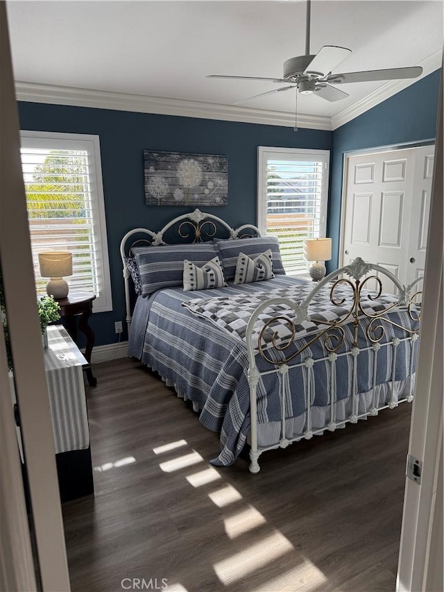 bedroom featuring baseboards, ceiling fan, ornamental molding, dark wood-style flooring, and a closet