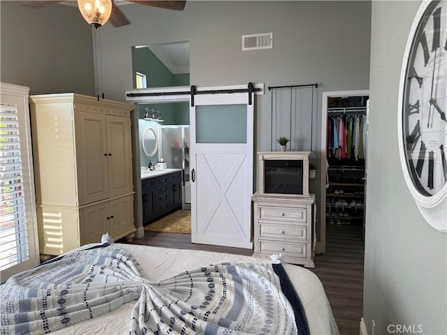 bedroom featuring a barn door, visible vents, wood finished floors, a spacious closet, and a closet