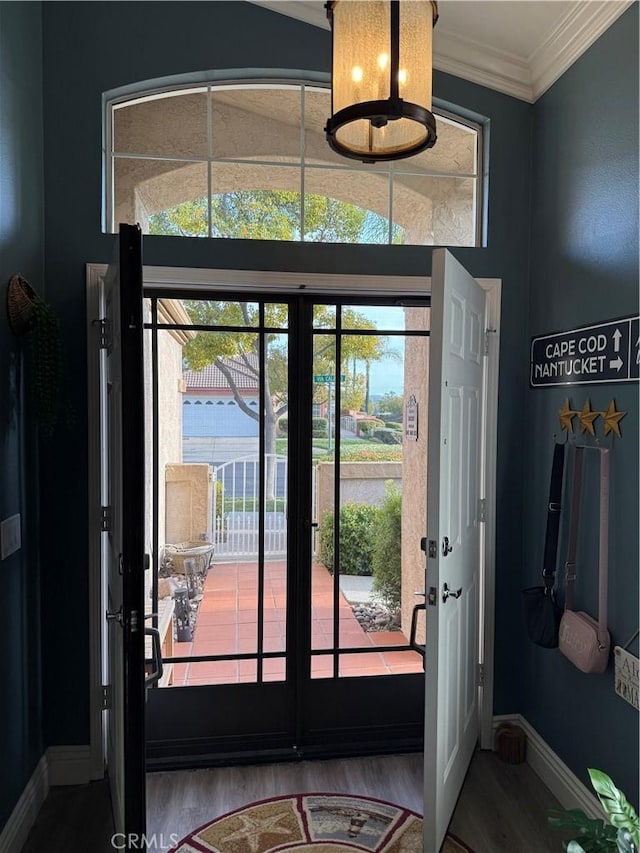 entryway featuring baseboards, ornamental molding, and wood finished floors