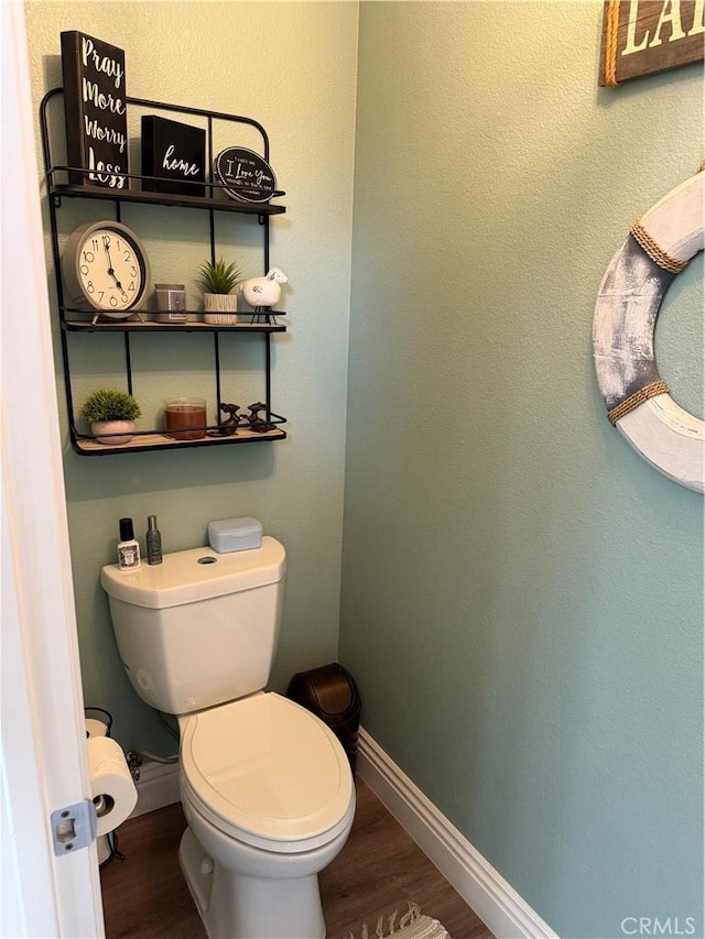 bathroom with toilet, wood finished floors, and baseboards
