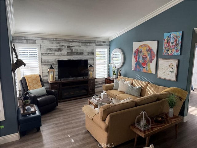 living area with baseboards, lofted ceiling, an accent wall, wood finished floors, and crown molding