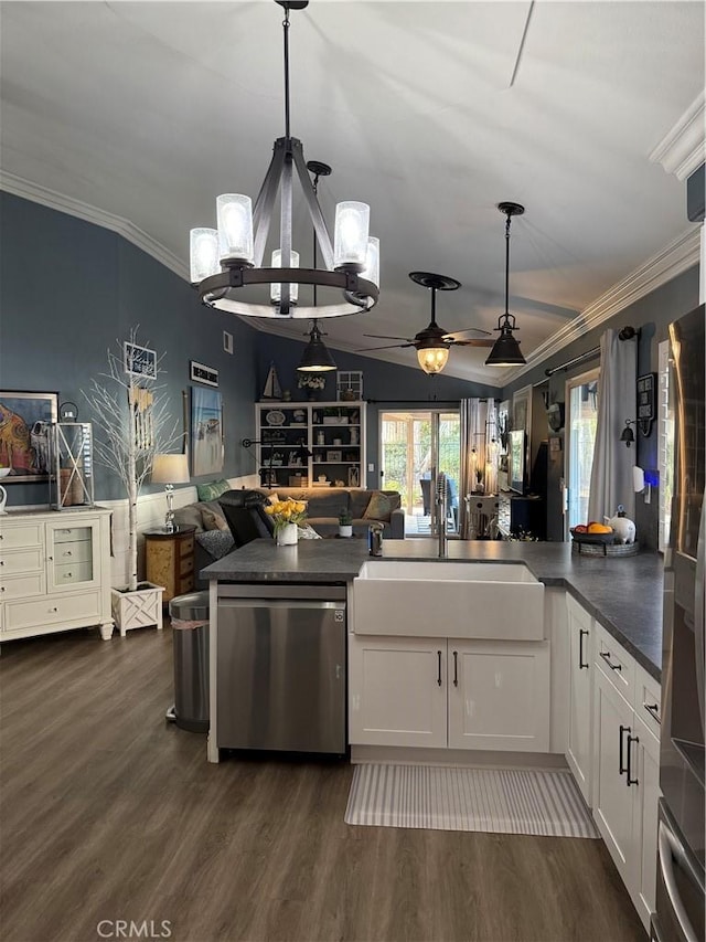 kitchen with a sink, open floor plan, appliances with stainless steel finishes, dark countertops, and dark wood finished floors