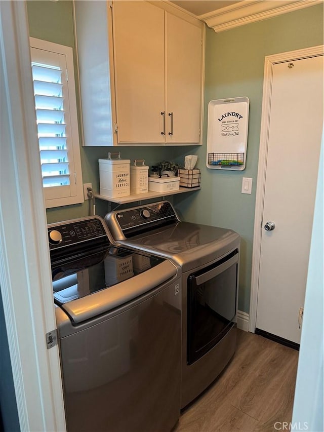 clothes washing area featuring washer and dryer, cabinet space, and wood finished floors