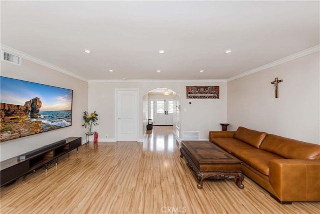 living area featuring arched walkways, visible vents, crown molding, and light wood-style flooring