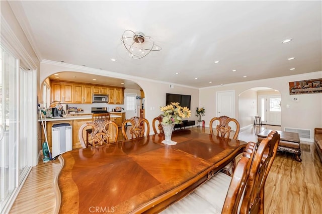 dining area featuring arched walkways, recessed lighting, visible vents, light wood-style floors, and ornamental molding