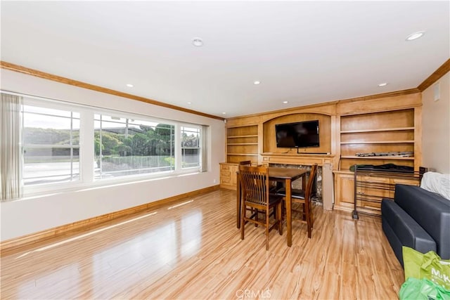 dining space featuring light wood-style floors, baseboards, and crown molding