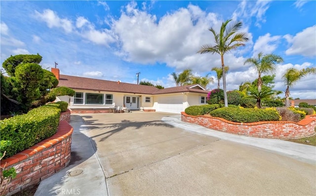 single story home with a garage, concrete driveway, and stucco siding