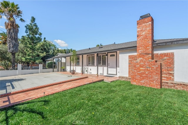 back of house with a yard, a chimney, stucco siding, a patio area, and fence