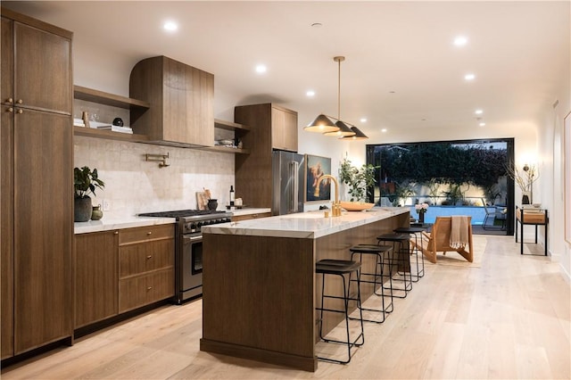 kitchen featuring open shelves, premium appliances, light wood-type flooring, and a sink