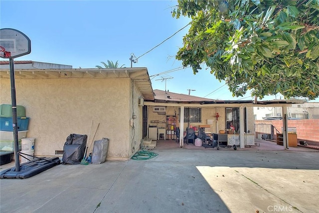 rear view of house featuring a patio area, fence, and stucco siding