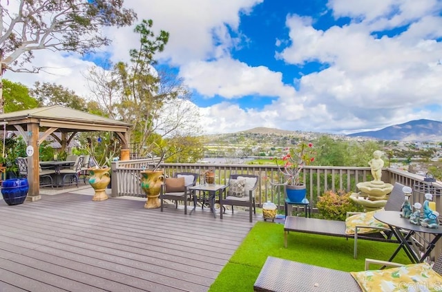 wooden deck with a gazebo, a mountain view, and outdoor dining area