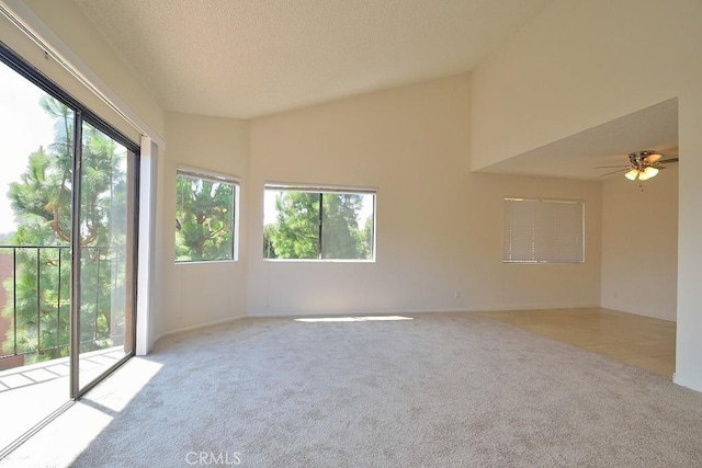 carpeted spare room with lofted ceiling, plenty of natural light, ceiling fan, and a textured ceiling