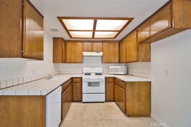 kitchen with white appliances, under cabinet range hood, and brown cabinets