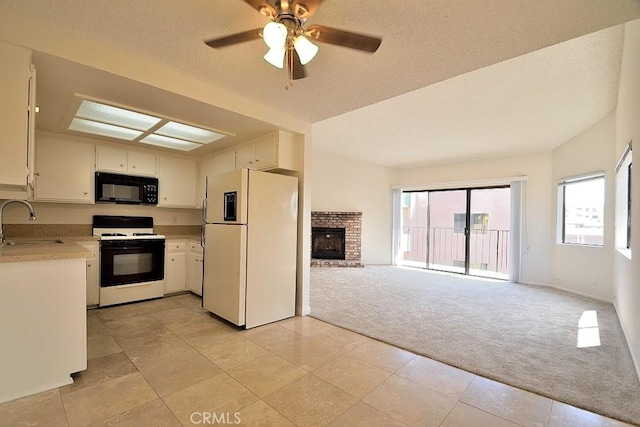 kitchen featuring range with gas cooktop, light countertops, freestanding refrigerator, light carpet, and black microwave