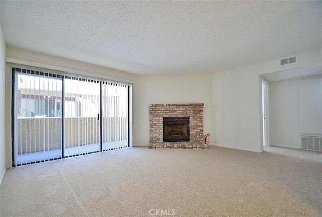 unfurnished living room featuring a textured ceiling, carpet floors, a brick fireplace, and visible vents