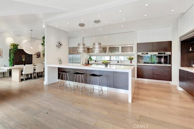 kitchen with light countertops, appliances with stainless steel finishes, light wood-style floors, white cabinets, and modern cabinets