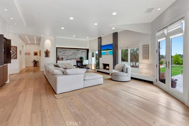 living area with light wood-style floors, a lit fireplace, baseboards, and recessed lighting