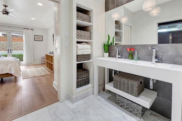 bathroom featuring double vanity, ensuite bath, a sink, french doors, and backsplash