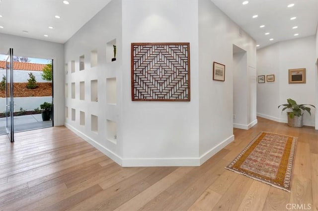 corridor with baseboards, light wood-style flooring, and recessed lighting