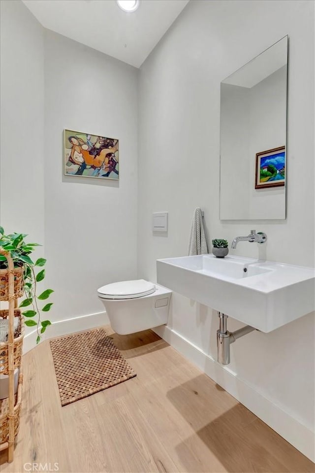 bathroom with baseboards, toilet, and wood finished floors