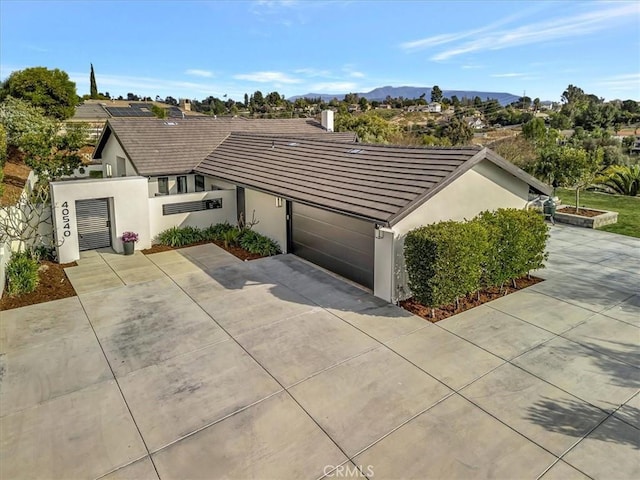 view of front of home with concrete driveway, a tiled roof, a gate, a mountain view, and stucco siding