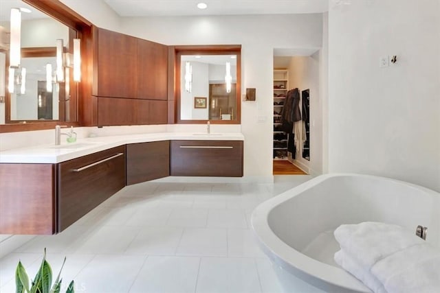 full bathroom featuring double vanity, a spacious closet, a soaking tub, and a sink