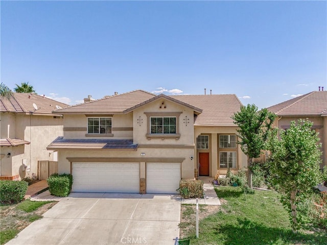 view of front of home with concrete driveway, a tile roof, an attached garage, and stucco siding