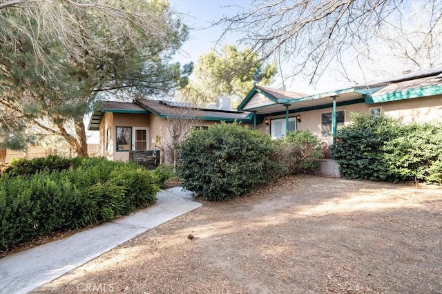 ranch-style home with solar panels and stucco siding