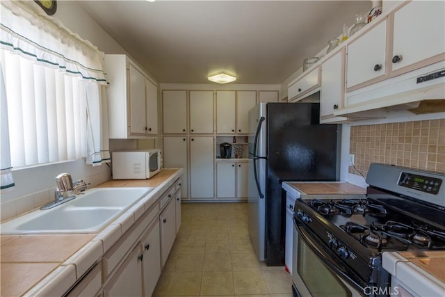 3648 Mira Pacific Dr, Oceanside, CA 92056 - kitchen featuring tile counters, decorative backsplash, appliances with stainless steel finishes, under cabinet range hood, and a sink