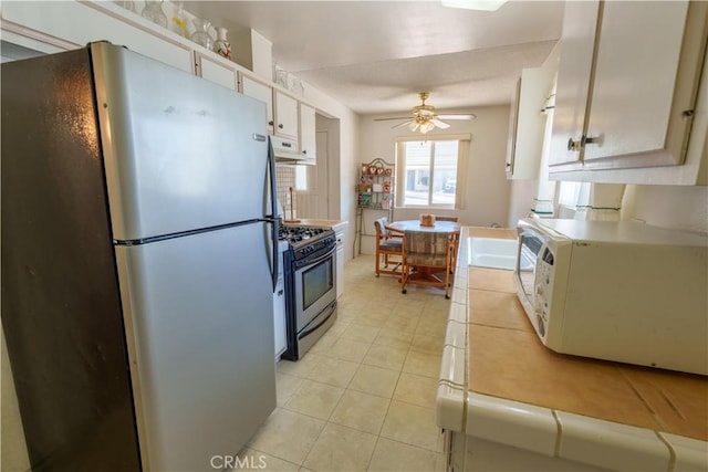 3648 Mira Pacific Dr, Oceanside, CA 92056 - kitchen featuring light tile patterned floors, white cabinets, ceiling fan, stainless steel appliances, and under cabinet range hood
