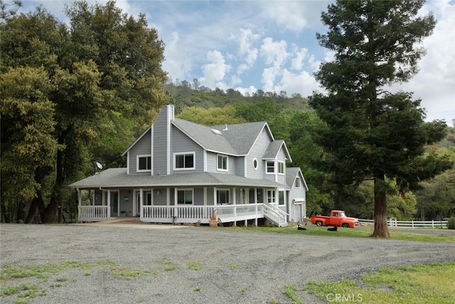 farmhouse-style home with a chimney, fence, and a porch