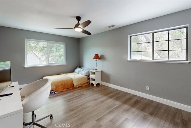 bedroom featuring ceiling fan, wood finished floors, visible vents, and baseboards