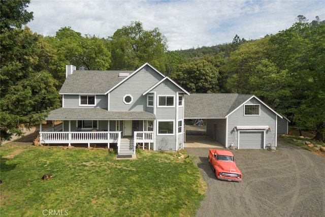 view of front of property featuring an attached carport, covered porch, driveway, a front lawn, and a view of trees