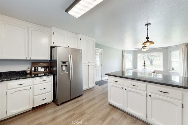 kitchen featuring light wood-style floors, dark stone counters, white cabinets, and stainless steel refrigerator with ice dispenser