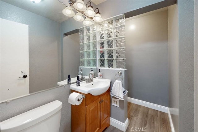 bathroom featuring toilet, baseboards, wood finished floors, and vanity