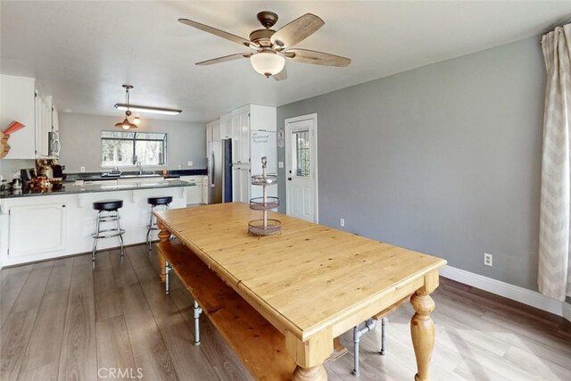 dining room with dark wood-style flooring, ceiling fan, and baseboards