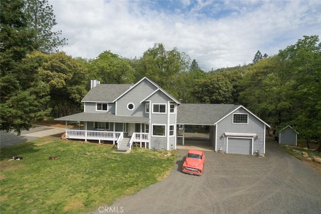 view of front of property featuring an outbuilding, covered porch, a chimney, a front yard, and a view of trees