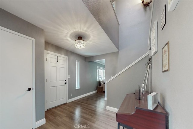 foyer entrance featuring an inviting chandelier, baseboards, and wood finished floors