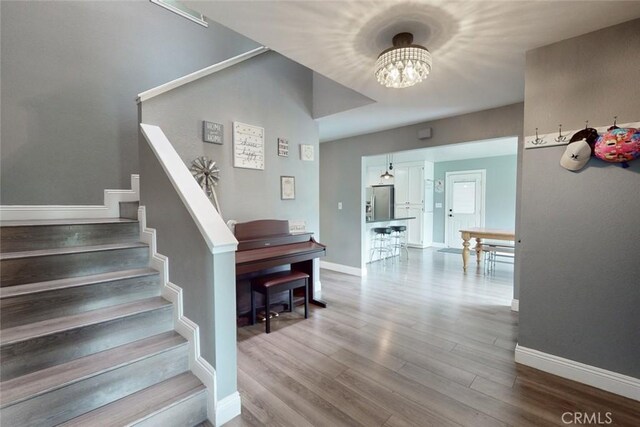 stairs featuring a chandelier, baseboards, and wood finished floors