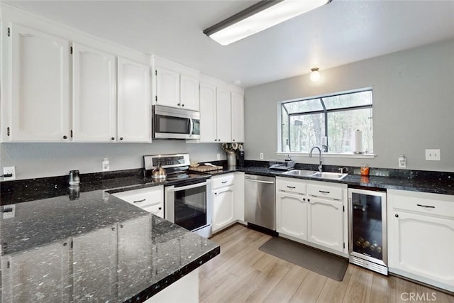 kitchen featuring beverage cooler, white cabinetry, stainless steel appliances, and a sink