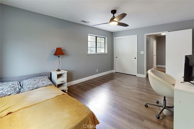 bedroom featuring baseboards, visible vents, a ceiling fan, wood finished floors, and a closet