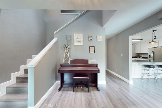 living area with stairs, light wood-style flooring, and baseboards