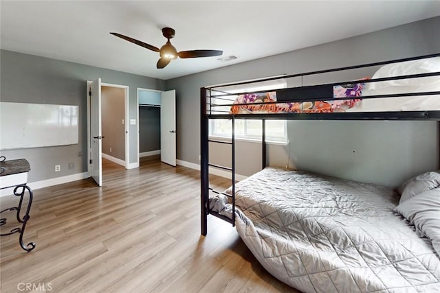 bedroom featuring a ceiling fan, baseboards, visible vents, and wood finished floors