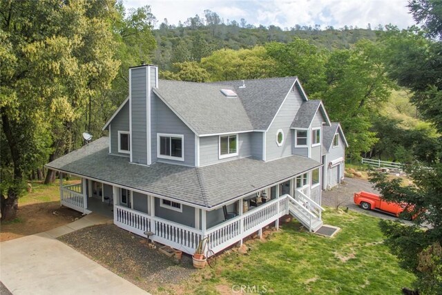 exterior space with covered porch, a shingled roof, a chimney, and a front lawn